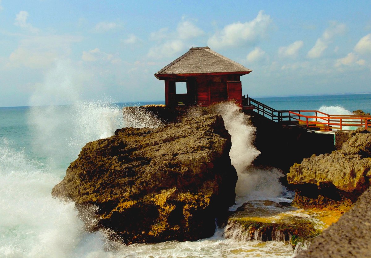 Waves breaking over the rocks below a pavilion by the sea