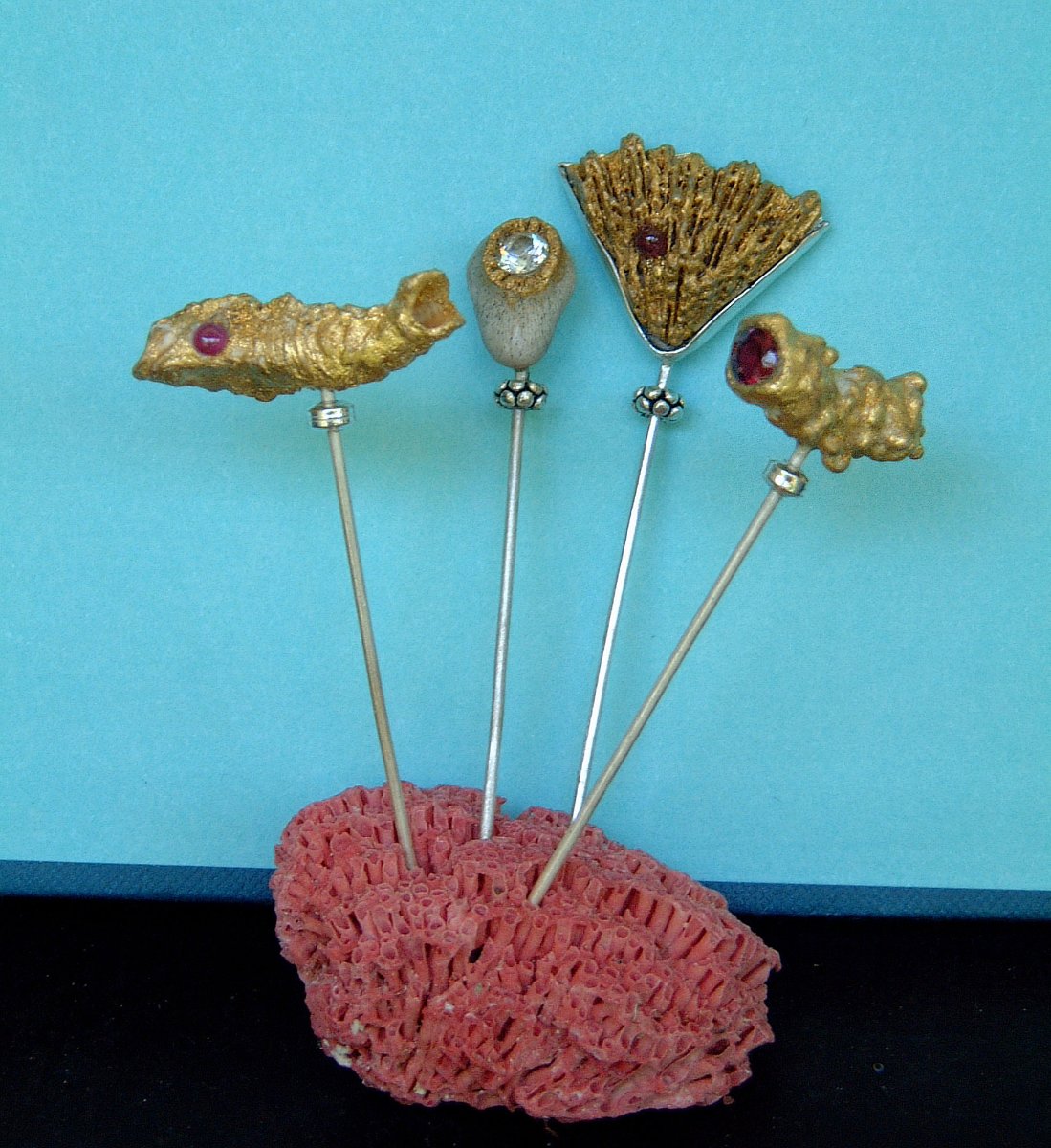 Four gilded hat pins set in red coral